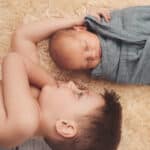 Baby mit Bruder liegend auf einem Fell