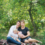 Familie sitzt auf einer Decke im Grünen