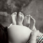 Füsse der Geschwister liegen auf dem Babybauch