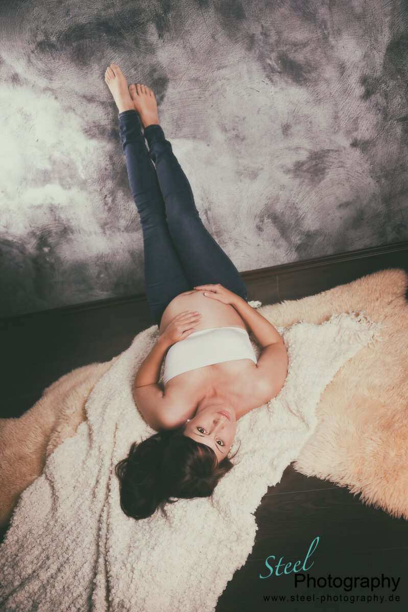 Schwangere liegend mit Beine an der Wand