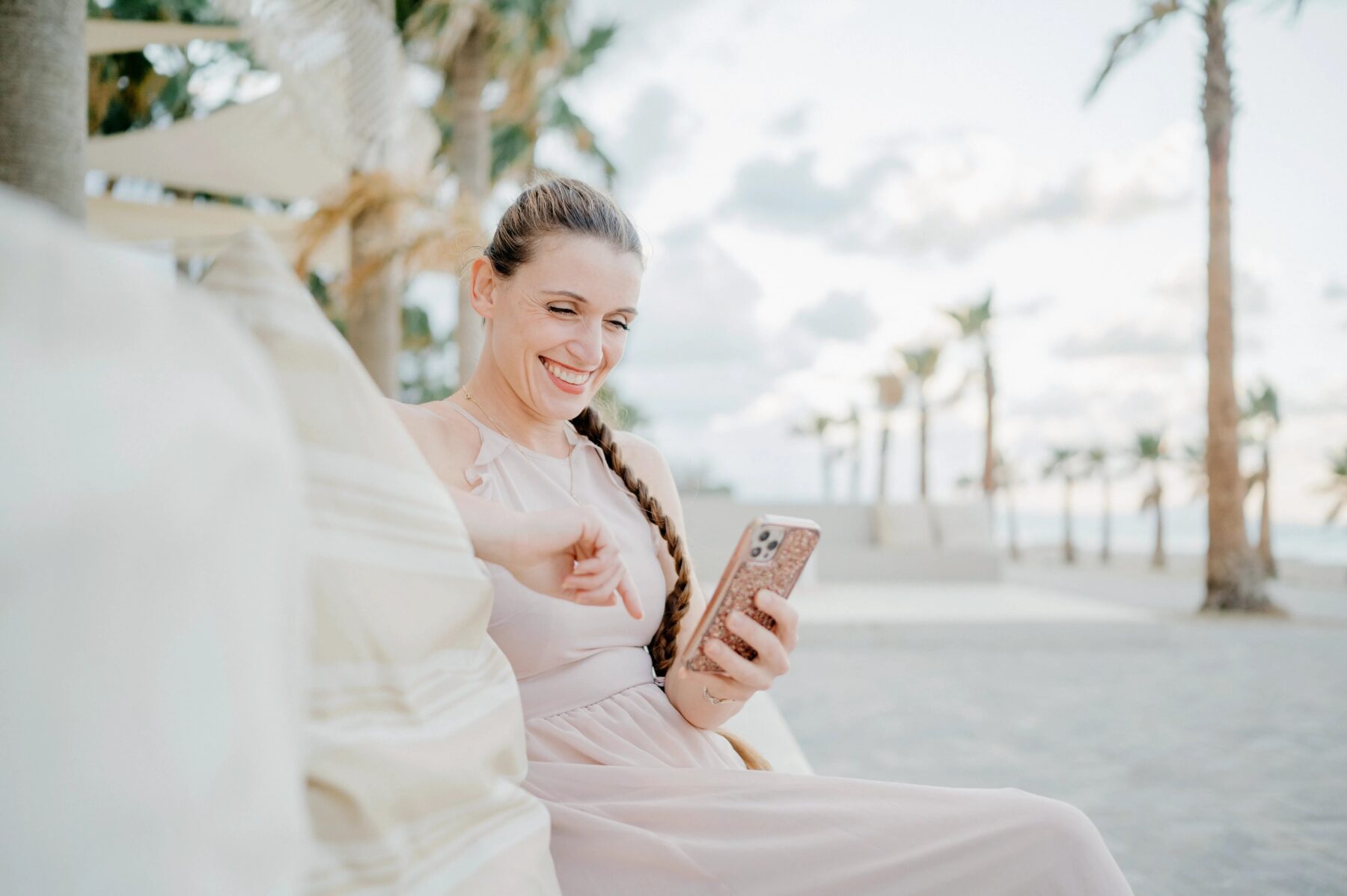 Personal Branding im Ausland, eine Frau sitzt am Meer mit Blick auf Ihr Handy